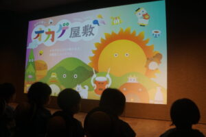 映画館のような大きいスクリーンで映像を見て・・・の様子